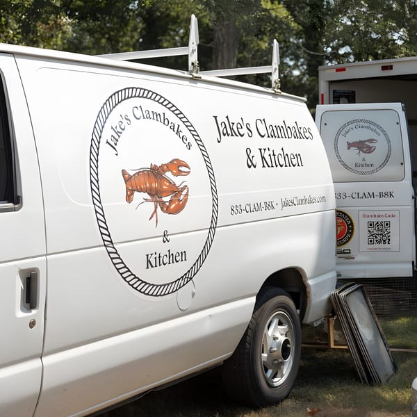 Two white Jake's Clambakes & Kitchen vans with lobster logos parked outdoors.