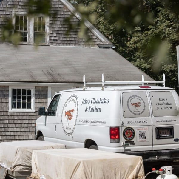 Jake's Clambakes & Kitchen catering van parked outside a shingled building.