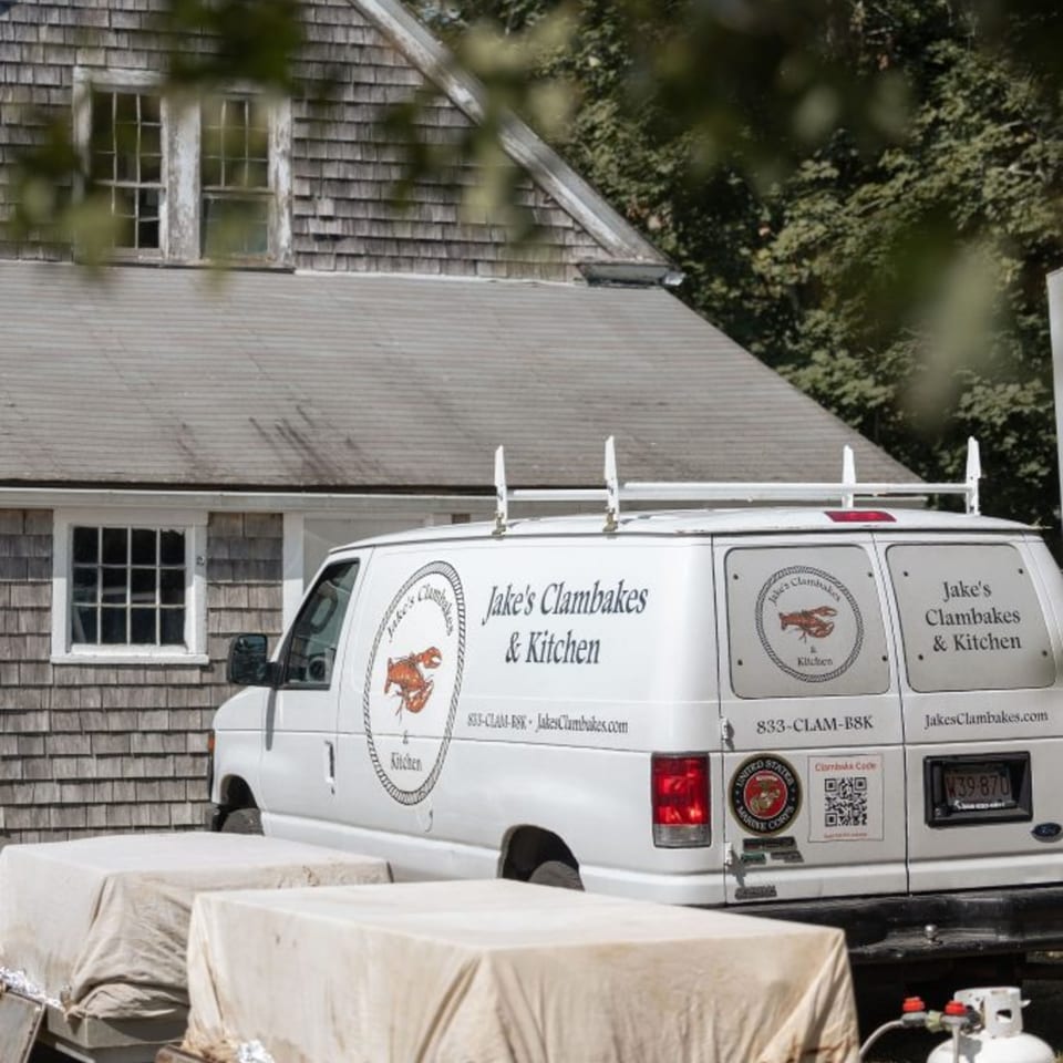 Jake's Clambakes & Kitchen catering van parked outside a shingled building.