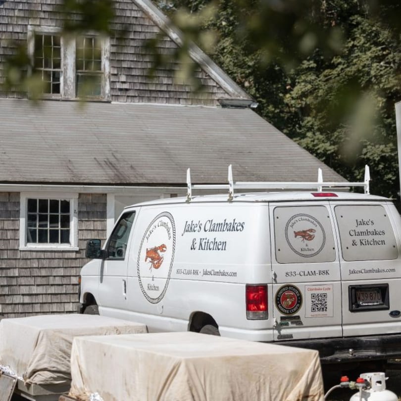 Jake's Clambakes & Kitchen catering van parked outside a shingled building.