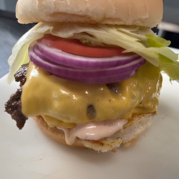 Cheeseburger with melted cheese, red onion, tomato, lettuce, and special sauce on a white bun.