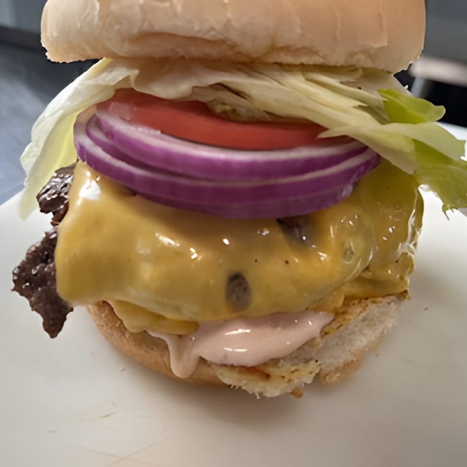 Cheeseburger with melted cheese, red onion, tomato, lettuce, and special sauce on a white bun.